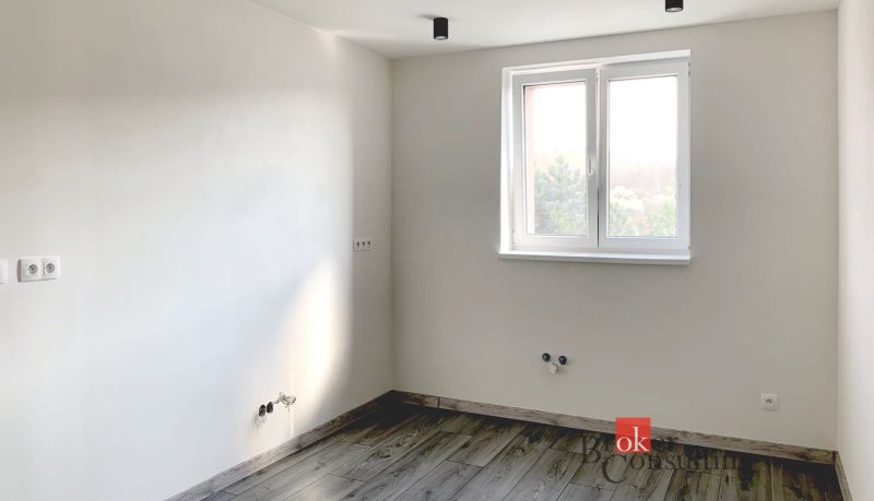 Krásny 1 izbový byt  45m2 + garáž - Jednoduchá miestnosť v 1-izbovom byte s podlahou s dreveným dekorom a bielymi stenami.