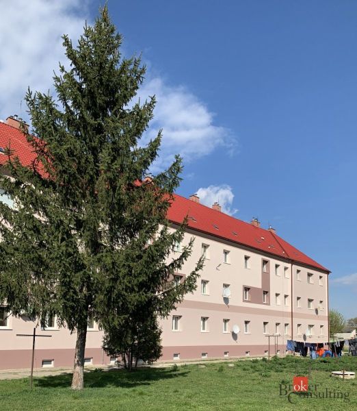 Krásny 1 izbový byt  45m2 + garáž - Budova s červenými strechami a pred ňou strom, na Železničnej ulici v Šahách.