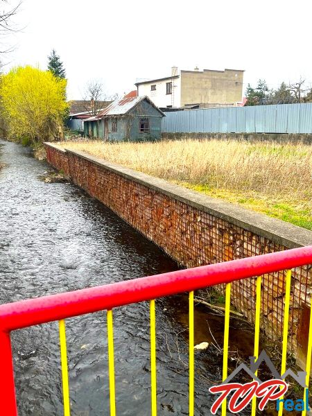 Rovinatý stavebný pozemok - Šaca - Obrázok z Jarkovej ulice, Košice - mestská časť Šaca, s riečkou a priľahlými pozemkami.