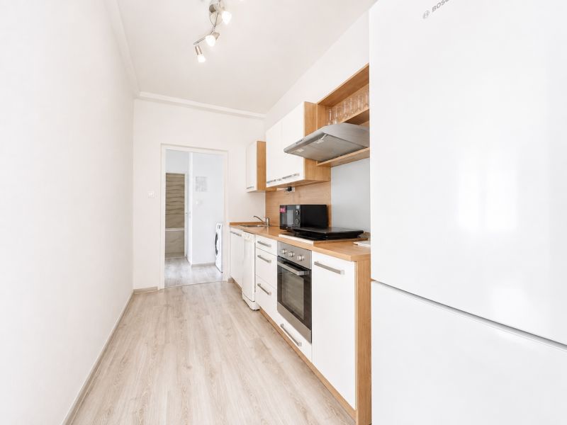 Na prenájom zariadený 4-izbový byt s balkónom I Ružinov |  - Kuchyňa so spotrebičmi a podlahou s dreveným dekorom v 4-izbovom byte.