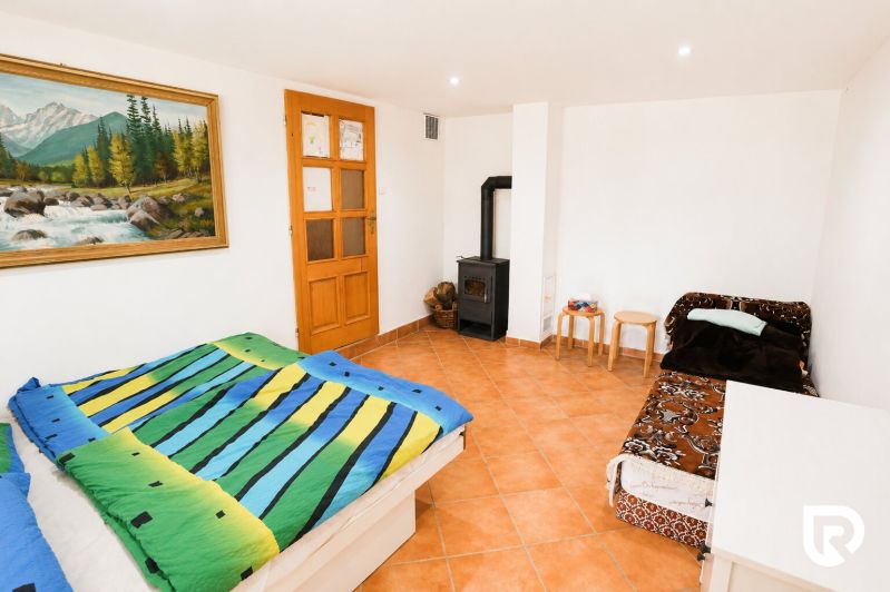 Investičná Príležitosť Chata - RD pri SKI MAKOV 4 959 m² pozem. - Spálňa s farebnou posteľnou bielizňou, pohovkou, kamnami a obrazom v rodinnom dome.