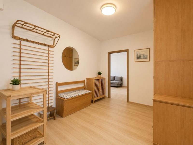 Pekný zariadený 3-izbový byt s 2 balkónmi | 85,3 m² | Petržalka I - Interiér 3-izbového bytu s podlahou s dreveným dekorom, lavicou a zrkadlom.