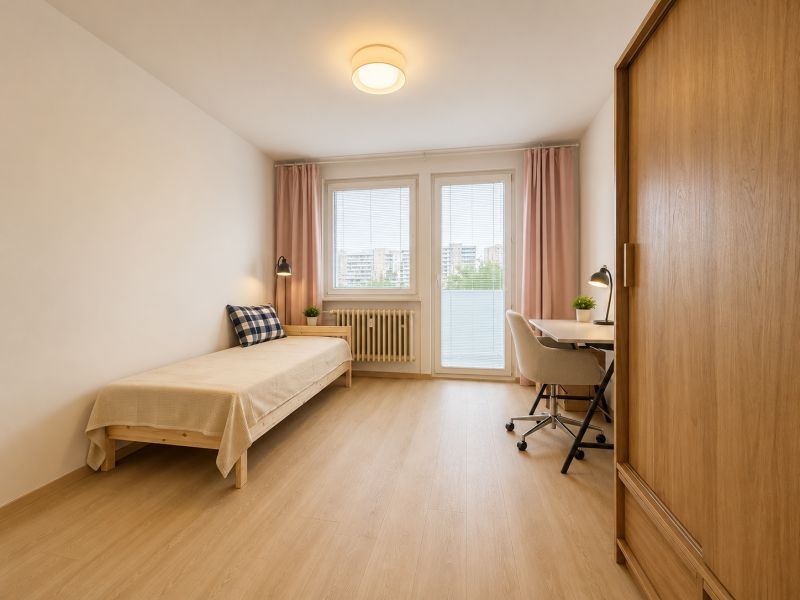 Pekný zariadený 3-izbový byt s 2 balkónmi | 85,3 m² | Petržalka I - Izba v 3-izbovom byte s posteľou, stolom a podlahou s dreveným dekorom.
