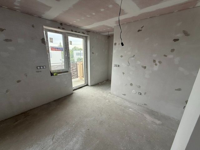 Ponúkame na predaj Rodinný dom v Rovinke na Platanovej ulici - Izba v rodinnom dome počas rekonštrukcie, s betónovou podlahou a veľkým oknom na stenu.