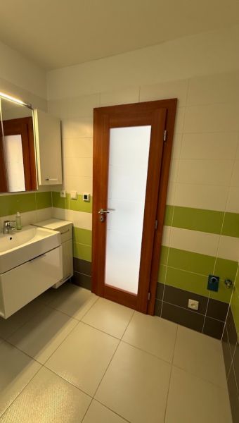 2- izbový byt na  Roľníckej ulici  - Kúpeľňa v 2-izbovom byte so zelenými obkladmi a skrinkou pod umývadlom.