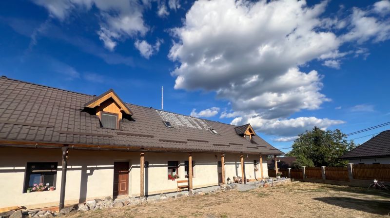 Atraktívny rodinný dom s veľkým pozemkom  – Hronská Dúbrava - Rodinný dom v Hronskej Dúbrave s veľkou strechou a skalnatým chodníkom v záhrade.