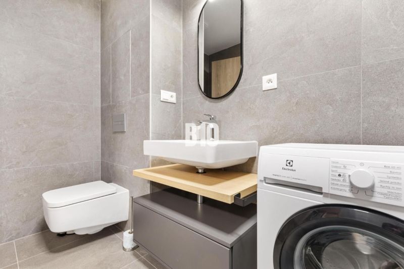 DOWNTOWN NA DOSAH – DIZAJNOVÝ 1-izbový apartmán s loggiou a výhľadom n - Kúpeľňa v 1-izbovom byte s modernou práčkou a sivým obkladom.