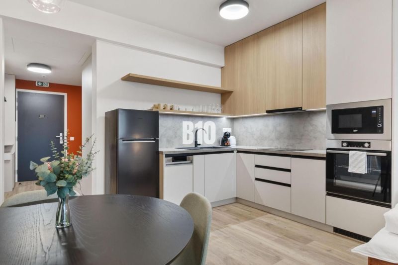 DOWNTOWN NA DOSAH – DIZAJNOVÝ 1-izbový apartmán s loggiou a výhľadom n - Kuchyňa s jedálenským stolom, spotrebičmi a podlahou s dreveným dekorom v 1-izbovom byte.