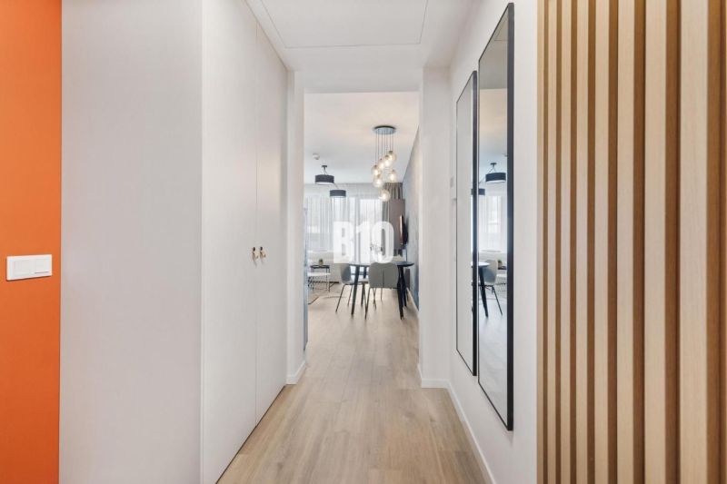 DOWNTOWN NA DOSAH – DIZAJNOVÝ 1-izbový apartmán s loggiou a výhľadom n - Chodba s podlahou s dreveným dekorom, zrkadlom a vstupom do obývacej časti.
