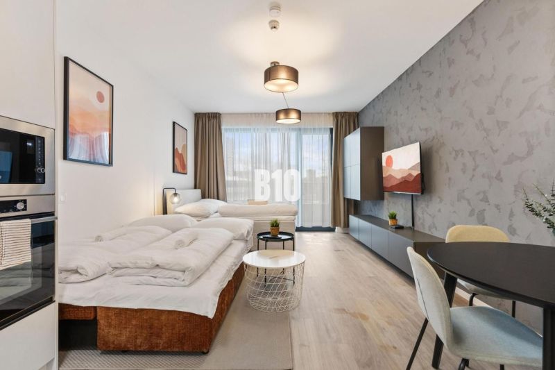 DOWNTOWN NA DOSAH – DIZAJNOVÝ 1-izbový apartmán s loggiou a výhľadom n - Komfortný obývací priestor v 1-izbovom byte s podlahou s dreveným dekorom a veľkými oknami.