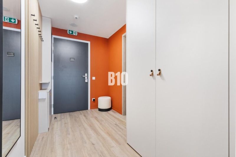 DOWNTOWN NA DOSAH – DIZAJNOVÝ 1-izbový apartmán s loggiou a výhľadom n - Vstupná hala 1-izbového bytu s podlahou s dreveným dekorom a oranžovou stenou.