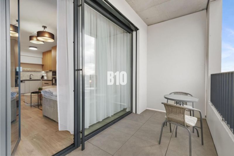DOWNTOWN NA DOSAH – DIZAJNOVÝ 1-izbový apartmán s loggiou a výhľadom n - Balkón s posedením a výhľad do 1-izbového bytu cez posuvné dvere.