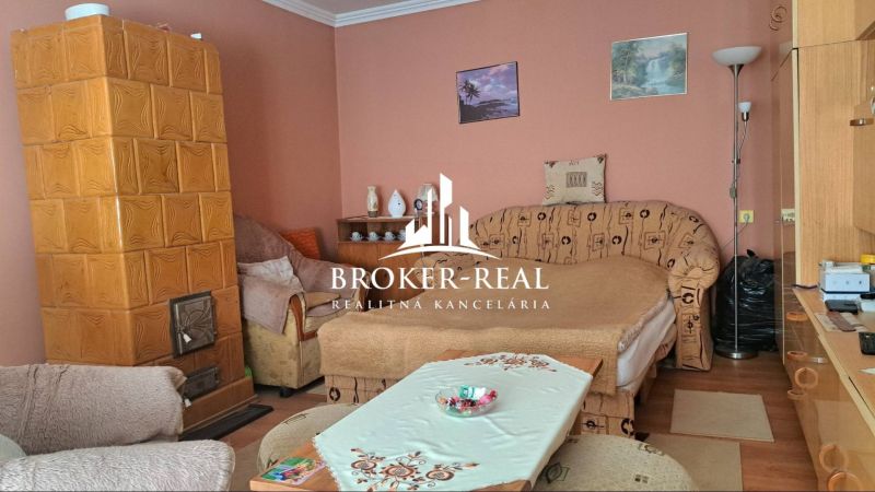 Rodinný dom 2 izb. Gőnc - Obývacia izba s kachľovou pecou a pohovkou v rodinnom dome.