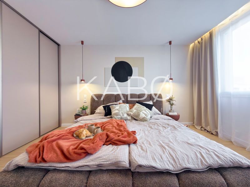 Moderný 3 izbový byt s balkónom a výhľadom na Zobor - Chrenová - Spálňa v 3-izbovom byte s posteľou, závesmi a skriňou; podlaha s dreveným dekorom.