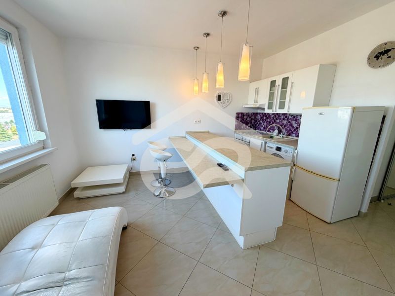 Na predaj kompletne prerobený 1 izbový byt, Vráble - Lúky, 36m2, 7/7 - Kuchyňa v 1-izbovom byte s barovými stoličkami a fialovým obkladom na stene.
