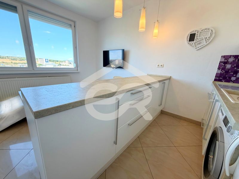 Na predaj kompletne prerobený 1 izbový byt, Vráble - Lúky, 36m2, 7/7 - Kuchyňa v 1-izbovom byte s práčkou, bielymi skrinkami a pracovnou doskou.