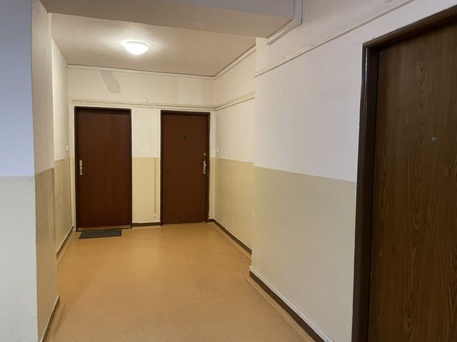 TOP Veľký rodinný 3-izbový byt s vlastným kúrením, loggiou a parkovaní - Chodba bytového domu s tromi dverami a svetlou stenou.