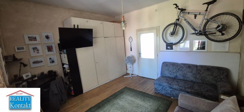 Na predaj 2 izbový tehlový byt 45m2 - Nové Zámky  - Obývacia izba 2-izbového bytu so sedačkou, televízorom a bicyklom na stene.