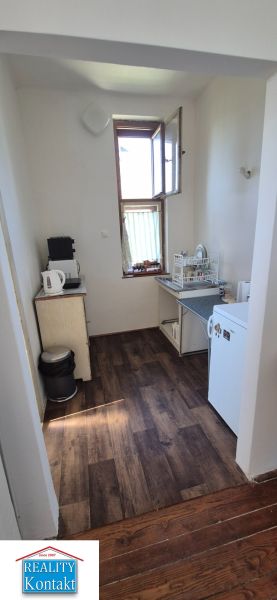 Na predaj 2 izbový tehlový byt 45m2 - Nové Zámky  - Kuchyňa v 2-izbovom byte s podlahou s dreveným dekorom a jednoduchým vybavením.