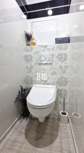 Moderný 3-izbový byt s pekným výhľadom - Jednoducho zariadené WC s dekoratívnymi obkladmi a podlahou s dreveným dekorom.