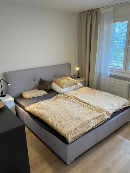 Prenájom pekný 3 izbový byt, ulica Staré záhrady,Bratislava II-Ružinov - Spálňa s veľkou posteľou, nočnými stolíkmi a podlahou s dreveným dekorom v 3-izbovom byte.