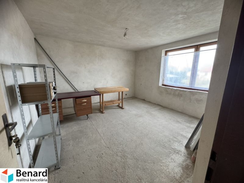 Rozostavaný rodinný dom Plavnica - Nedokončená miestnosť v Rodinnom dome s oknom a kovovým regálom.