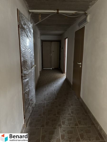 Rozostavaný rodinný dom Plavnica - Chodba v rodinnom dome, s béžovým obkladom na podlahe a plastovými dverami.