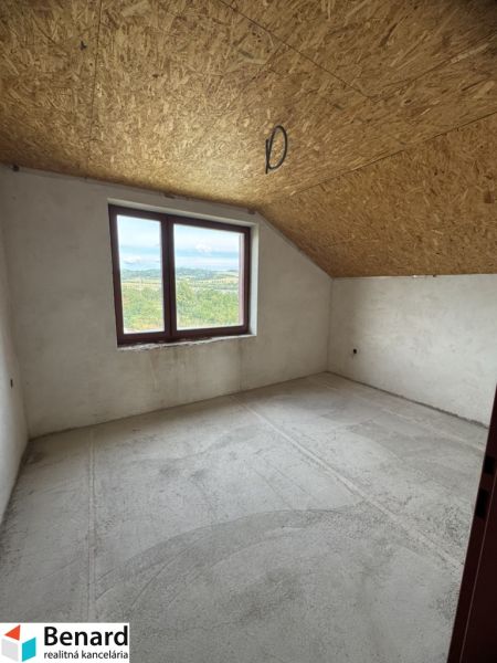 Rozostavaný rodinný dom Plavnica - Pohľad do prázdnej miestnosti rodinného domu so strešným oknom a betónovou podlahou.