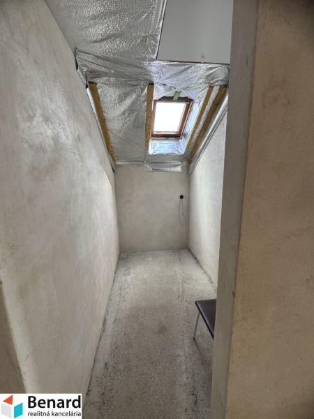 Rozostavaný rodinný dom Plavnica - Úzka miestnosť s betónovou podlahou a strešným oknom v rodinnom dome.