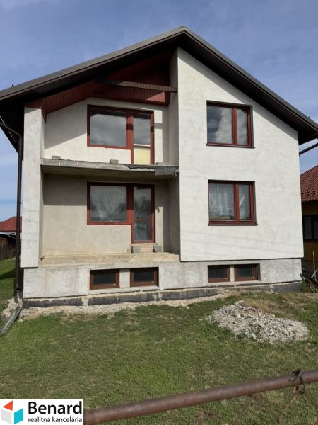 Rozostavaný rodinný dom Plavnica - Rodinný dom v Plavnici s jednoduchou fasádou a novými oknami, s trávnatým pozemkom.