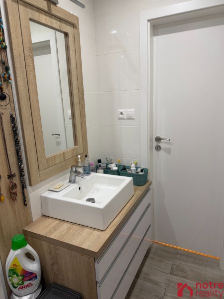 2,5 izbový byt v centre Lučenca - Kúpeľňa v 2-izbovom byte s umývadlom a nábytkom s dreveným dekorom.