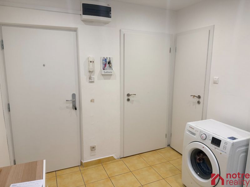 2,5 izbový byt v centre Lučenca - Vstupná chodba v 2-izbovom byte so žltou dlažbou a práčkou.