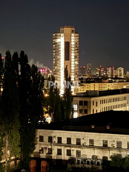 PENTHOUSE – moderný 2i byt s výnimočnou 69 m² terasou, AHOJ PARK - Večerný pohľad na osvetlený výškový dom v Bratislave, Novom Meste na Sliačskej ulici.