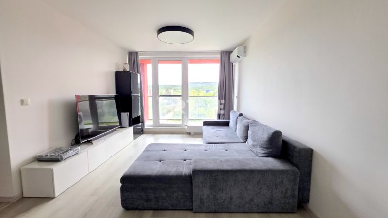 MODERNÝ 3i BYT, NOVOSTAVBA ČEREŠNE, LOGGIA, KLÍMA, PARKING, Polianky - Obývačka v 3-izbovom byte s veľkou pohovkou, televízorom a výhľadom cez balkónové dvere.