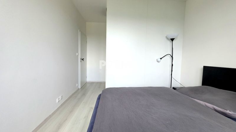 MODERNÝ 3i BYT, NOVOSTAVBA ČEREŠNE, LOGGIA, KLÍMA, PARKING, Polianky - Spálňa s posteľou, stojacou lampou a podlahou s dreveným dekorom v 3-izbovom byte.