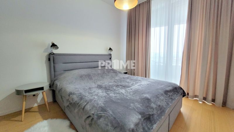 ŠTÝLOVÝ 2i byt, PARKING, KLÍMA, PARKING, Čulenova ulica, SKY PARK - Spálňa s posteľou, nočným stolíkom, závesmi a podlahou s dreveným dekorom v 2-izbovom byte.