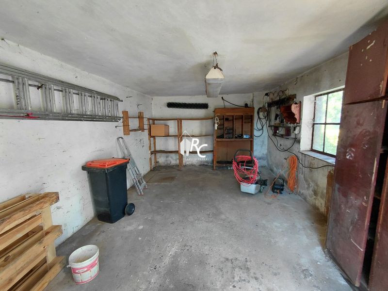 Rodinný dom Martin – Podháj, 5 izieb a pozemok 621 m² - Garáž v rodinnom dome s nástrojmi, paletami a rebríkom. Okná prepúšťajú denné svetlo.