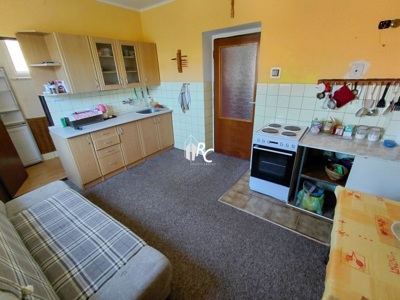 Rodinný dom Martin – Podháj, 5 izieb a pozemok 621 m² - Kuchyňa v rodinnom dome s plynovým sporákom a kobercovou podlahou.