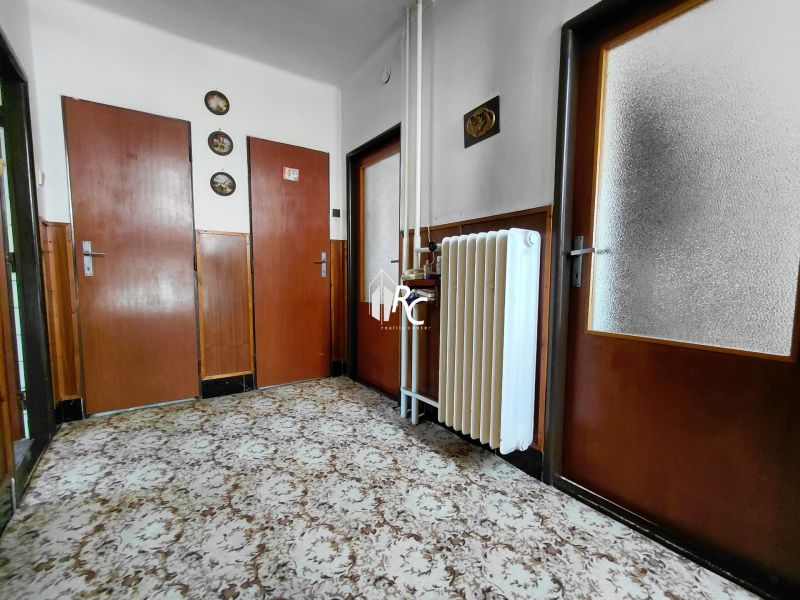 Rodinný dom Martin – Podháj, 5 izieb a pozemok 621 m² - Chodba v rodinnom dome s kobercom, drevenými dverami a radiátorom na stene.