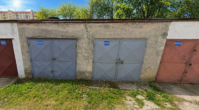 PREDAJ - Murovaná garáž v rad. zástavbe na Gašparíkovej ulici, Ružinov - Garáže na Gašparíkovej ulici v Bratislave-Ružinove, obklopené trávou a stromami.