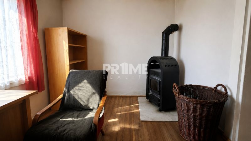 Jedinečný pozemok s domom pod lesom vo Svätom Jure – Neštich  - Izba s krbovou pecou, drevenou skriňou a podlahou s dreveným dekorom.