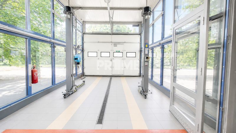 MODERNÝ, ZABEHNUTÝ, KOMPLETNE ZARIADENÝ AUTOSERVIS, LOZORNO - Priestranné výrobné priestory s veľkými sklenenými dverami a vybavením na opravu vozidiel.