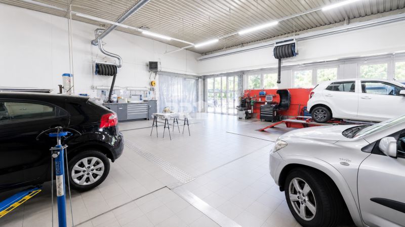 MODERNÝ, ZABEHNUTÝ, KOMPLETNE ZARIADENÝ AUTOSERVIS, LOZORNO - Výrobné priestory s autami a opravnými zariadeniami, svetlé s bielymi stenami.