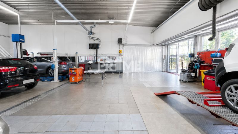 MODERNÝ, ZABEHNUTÝ, KOMPLETNE ZARIADENÝ AUTOSERVIS, LOZORNO - Výrobné priestory s autami a závesmi na dlažbe, zariadené servisným vybavením.