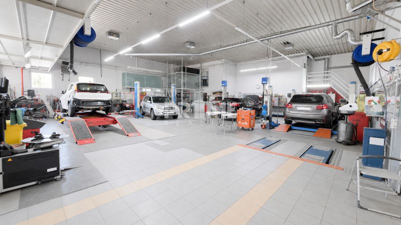 MODERNÝ, ZABEHNUTÝ, KOMPLETNE ZARIADENÝ AUTOSERVIS, LOZORNO - Výrobné priestory s automobilmi na zdvihákoch, dielenské vybavenie, biela strecha.