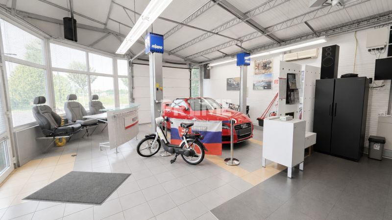 MODERNÝ, ZABEHNUTÝ, KOMPLETNE ZARIADENÝ AUTOSERVIS, LOZORNO - Interiér výrobných priestorov s autom, bicyklom a kreslami, podlaha s dlaždicami.