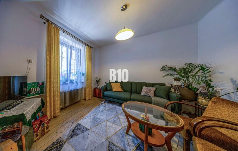 Priestranný 5-izbový rodinný dom (190 m²) s krásne upraveným 13a pozem - Obývacia izba v rodinnom dome s pohovkou, kobercom a podlahou s dreveným dekorom.