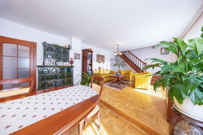 Priestranný 5-izbový rodinný dom (190 m²) s krásne upraveným 13a pozem - Obývacia izba v rodinnom dome s podlahou s dreveným dekorom, pecou a dreveným schodiskom.