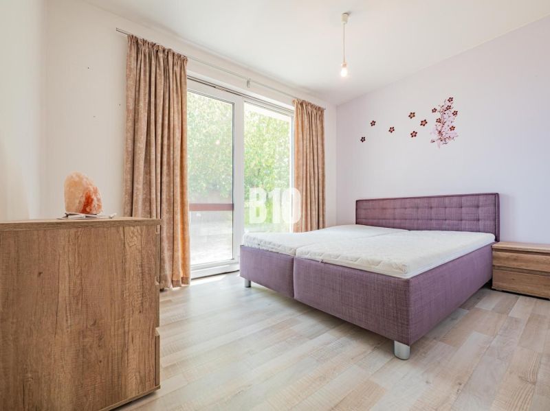ŠIKOVNÝ 5 izbový dom blízko Nitry - Spálňa v rodinnom dome s posteľou, fialovými doplnkami a podlahou s dreveným dekorom.