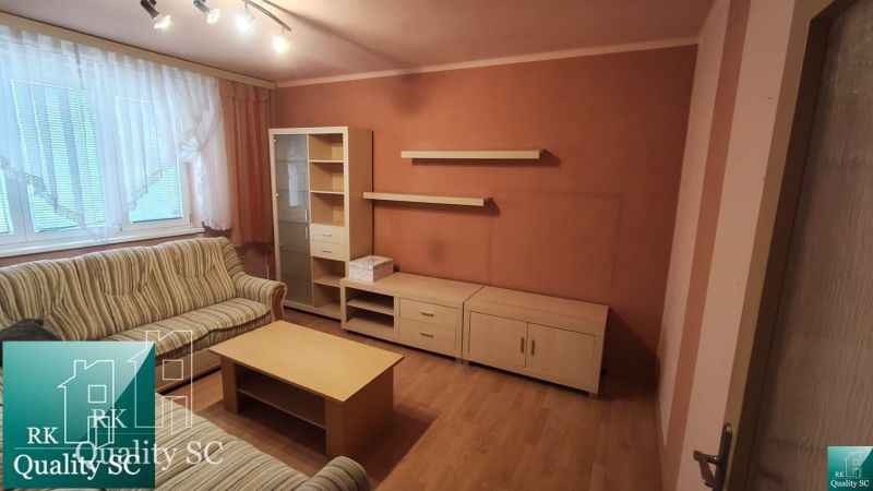 Okres SENEC - obec ČATAJ - NA PREDAJ 4. izbový priestranný mezonetový  - Obývacia izba s pohovkou, dreveným dekorom podlahy a nábytkom v 4-izbovom byte.